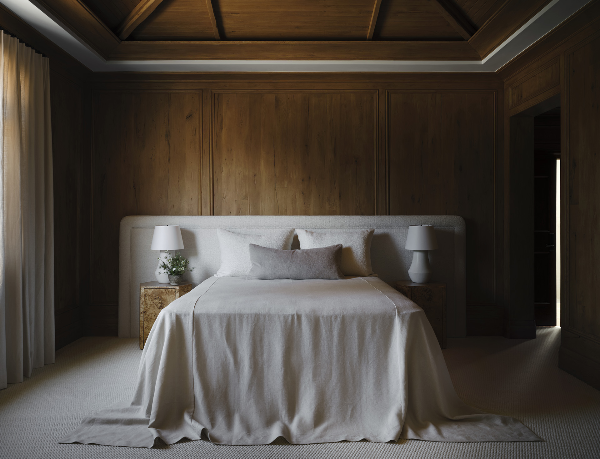 Upholstered bed against warm wood paneling