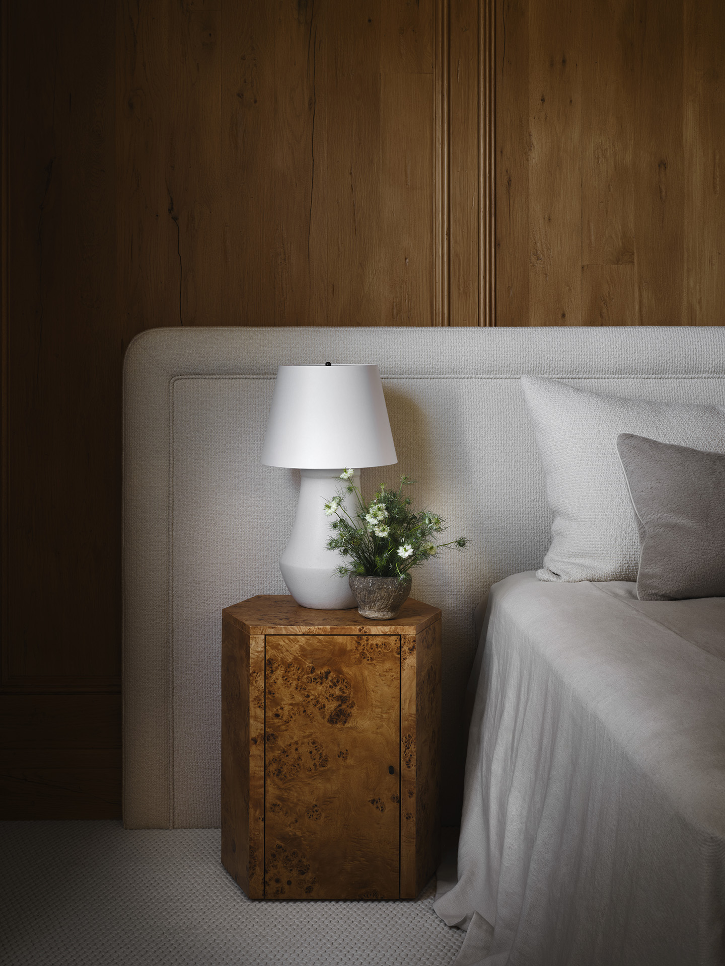 Tailored upholstered headboard against wood paneling
